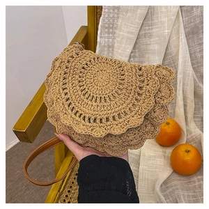 Detail of bohemian woven bag featuring intricate crochet patterns and brown leather strap