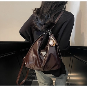 Close-up of a large coffee brown patent leather tote bag featuring a triangle logo plaque