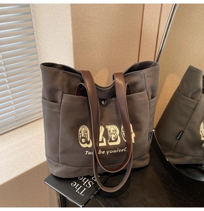 Dettaglio della borsa tote in tela con stampa ALBC e manici in pelle color marrone