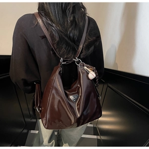 Detail of glossy coffee brown patent leather tote with silver triangle metal logo