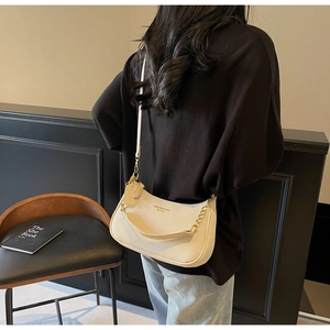 Detail of beige half-moon woven bag with gold chain strap and leather shoulder handle