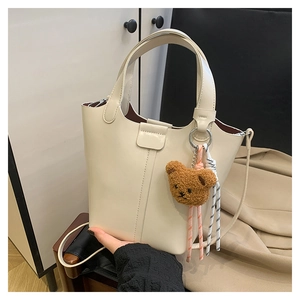 Detalle del bolso tote blanco crema con colgante de oso de peluche y cuerda tejida