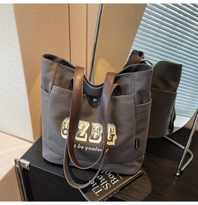 Dettaglio della borsa tote in tela grigio scuro con manici in pelle marrone e stampa 6ZBG