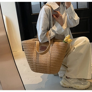 Close-up of woven straw tote bag with brown leather patch and large interior space