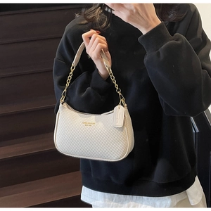 Close-up of off-white textured hobo bag with gold chain strap and lettered logo