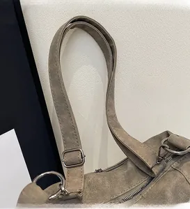 Detail of adjustable wide shoulder strap and metal hardware on matte taupe crossbody bag