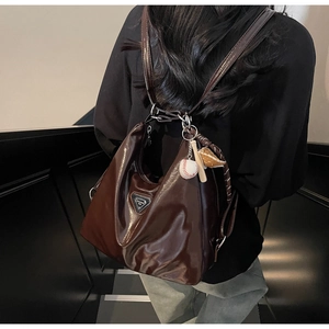 Deep brown glossy tote bag with baseball pendant shown on model in a modern staircase
