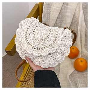 Close-up of white woven boho crossbody bag with layered scalloped crochet and brown leather strap