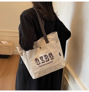 Dettaglio della borsa tote in tela crema con tasca laterale e tracolla marrone scuro
