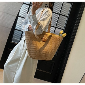 Close-up of natural woven straw tote bag with brown leather patch and vacation vibe