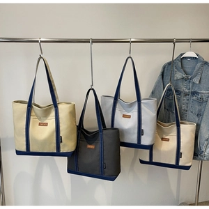 Detailed view of canvas tote bags in multiple colors with leather logo and sturdy handles