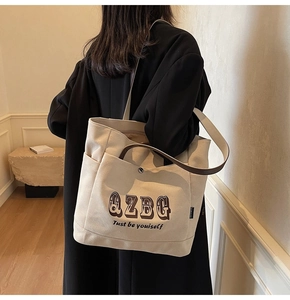 Dettaglio della borsa tote in tela beige con stampa QZBG e tracolla marrone