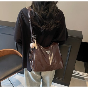 Macro detail of glossy dark brown tote bag with baseball charm and metal logo