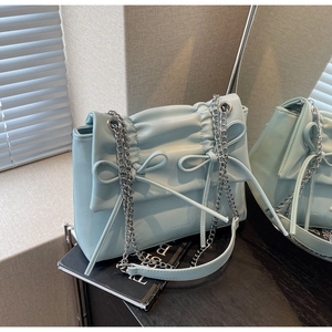 Detail showing the pleated soft texture and bow tie design on the baby blue handbag