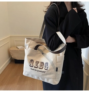 Dettaglio della borsa tote in tela crema con manici in pelle indossata dalla modella