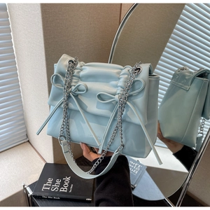 Detail of light blue pleated handbag featuring bow accents and silver chain strap