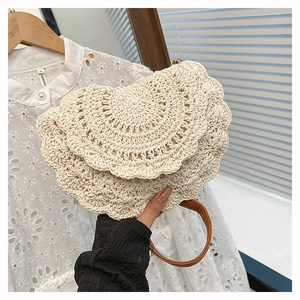 Detailed close-up of bohemian woven cotton bag featuring scalloped flap and leather handle