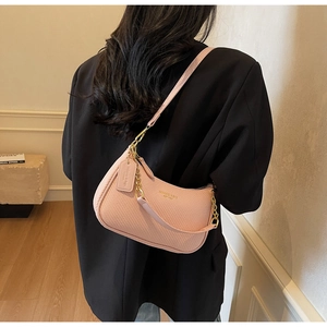 Pink woven leather hobo bag with gold chain detail worn over a woman's shoulder