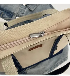 Detail of a smooth metal zipper on a durable beige canvas tote bag with blue trim