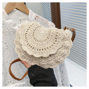 Close-up of bohemian hand-woven cream cotton crochet bag with stylish brown leather strap