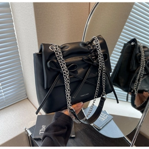 Detail showing black ruched leather bag with bow drawstring and silver chain strap