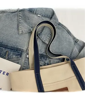Detail of canvas tote handle with contrast stitching and reinforced blue webbing strap