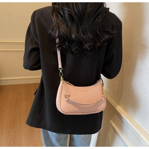 Detail of light pink woven half-moon bag with gold chain strap and embossed branding