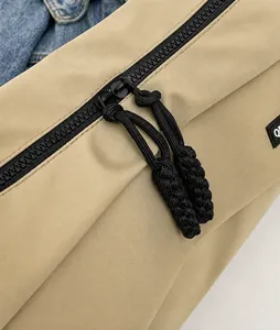 Detailansicht des glatten schwarzen Metallreißverschlusses mit Kordelzug am Khaki-Beutel