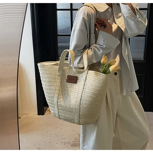 Close-up of woven straw tote bag featuring detailed texture and brown leather label patch
