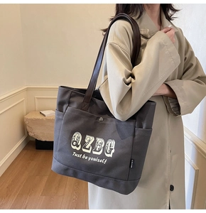 Dettaglio della borsa tote in tela grigio scuro con tasca frontale e bottone a pressione in metallo