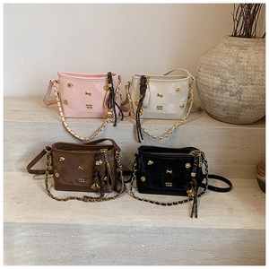 Four patent leather tote bags in pink, white, brown, and black displayed on stone steps