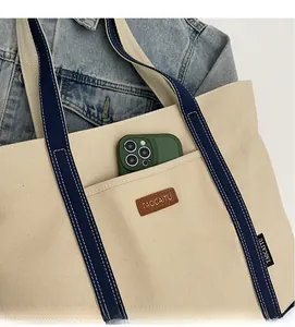 Close-up of durable front pocket on canvas tote bag with leather logo detail