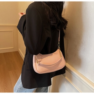 Detail of pink semi-circle crossbody bag with gold chain and woven leather texture