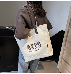 Dettaglio della borsa tote in tela color crema con manici in pelle e stampa QZBG