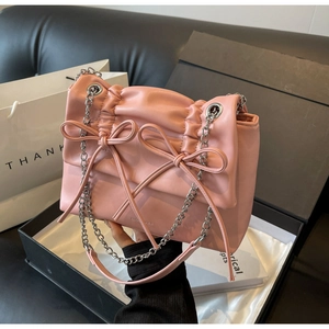 Close-up of pink pleated leather crossbody bag with bow details and silver chain