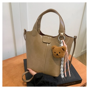 Detalle de bolso cubo de cuero PU caqui con un colgante de oso y asa redonda