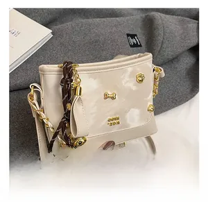 Close-up of cream leather bag featuring unique gold bone and cat-shaped hardware accents
