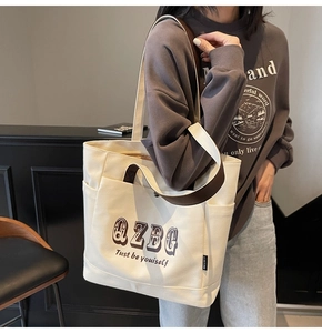 Dettaglio della borsa tote in tela con manici in pelle marrone e tasche laterali pratiche