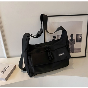 Detailopname van zwarte crossbody tas met verstelbare riem en merklabel detail