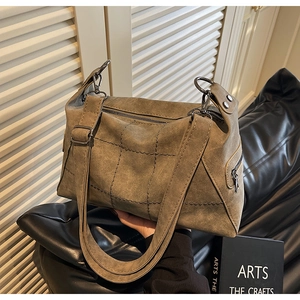 Detailed view of vintage matte shoulder bag with cross stitching and metal zipper