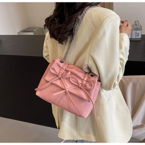 Detailed shot of pink crossbody bag featuring double bows and silver chain strap details