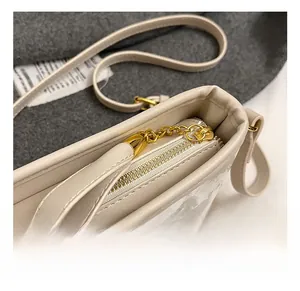 Macro shot of polished gold-toned zipper hardware on cream leather tote bag details