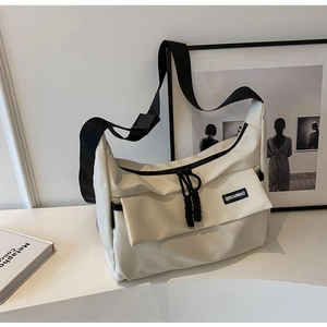 Detail van beige messenger tas met verstelbare riem en logo voor dagelijks gebruik