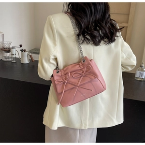 Detail of pink crossbody bag with pleated texture and decorative ribbon bow design