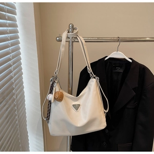 Close-up of beige Hobo tote bag with metal logo and playful baseball charm detail