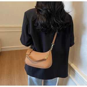 Detail of a brown leather crescent shoulder bag with gold chain and adjustable strap