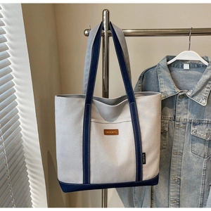 Detail of contrast stitching and blue canvas trim on the beige shoulder tote bag