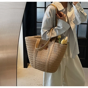 Detail of hand-woven straw tote bag with brown leather patch and large interior capacity