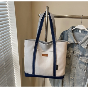 Detail of canvas tote bag with contrast navy blue straps and exterior pocket detail