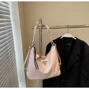 Detail of soft pink leather tote featuring a baseball charm and triangle logo on a stand
